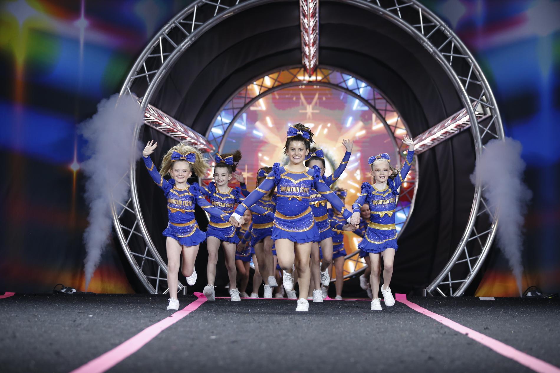 Mountain State all star athletes running onto the competition floor in royal blue and gold uniforms