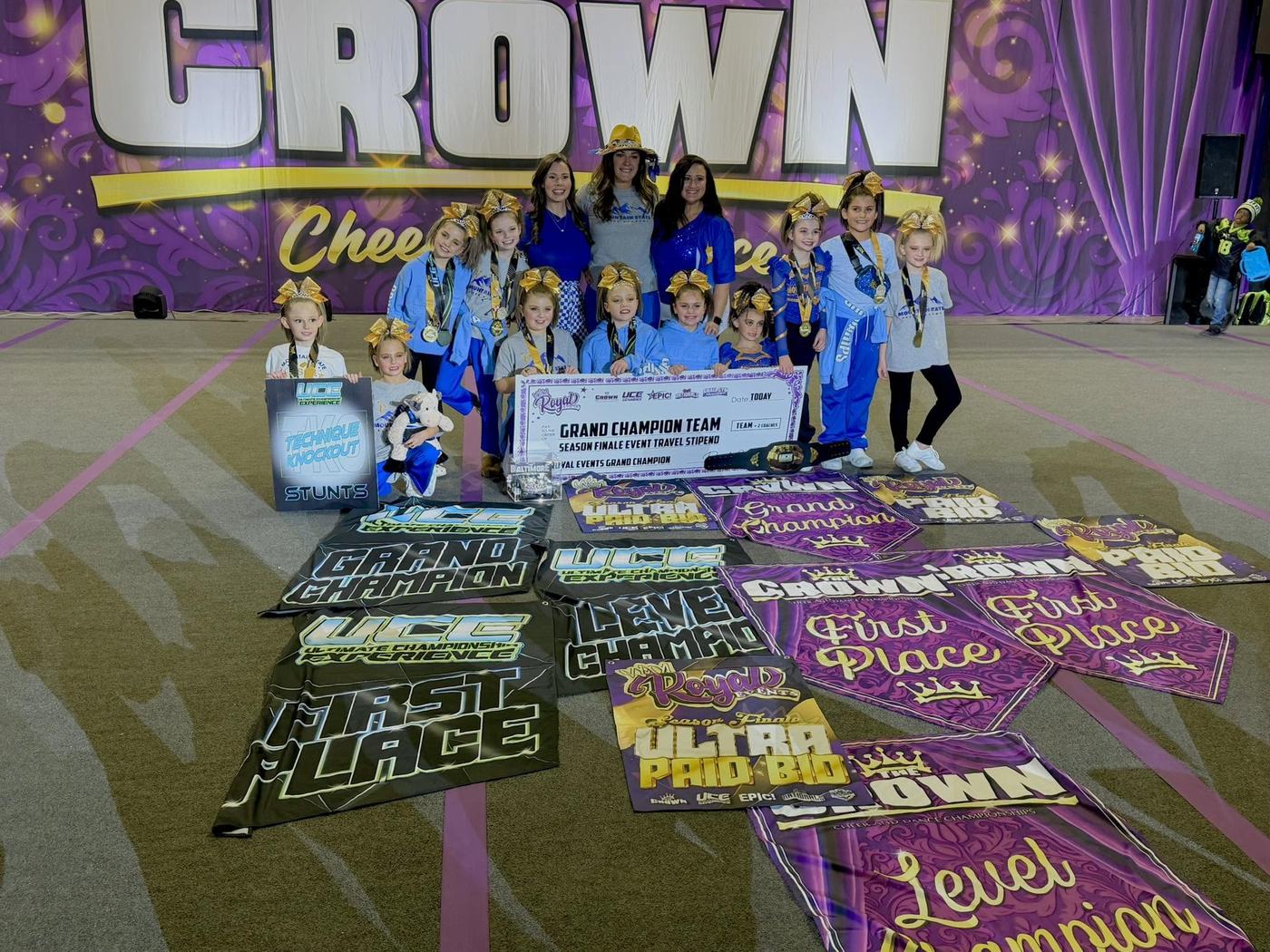 Athletes and coaches with grand champion banners and a championship belt
