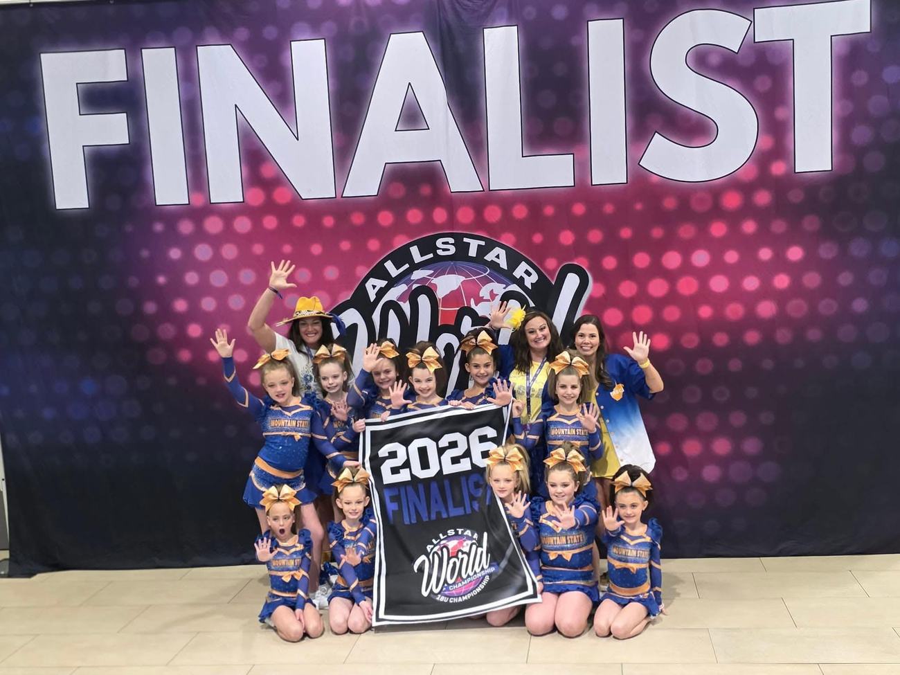 Mountain State athletes and coaches holding a 2026 Allstar World Championship finalist banner
