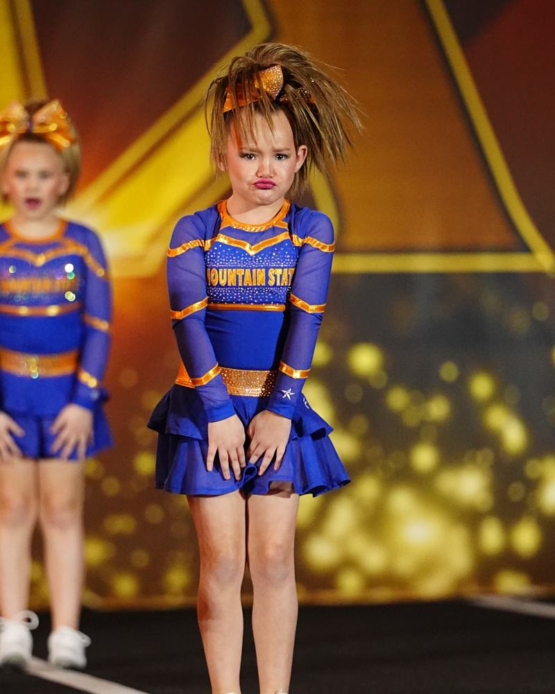 Fireflies athlete in a gold bow making a big pouty face during the routine